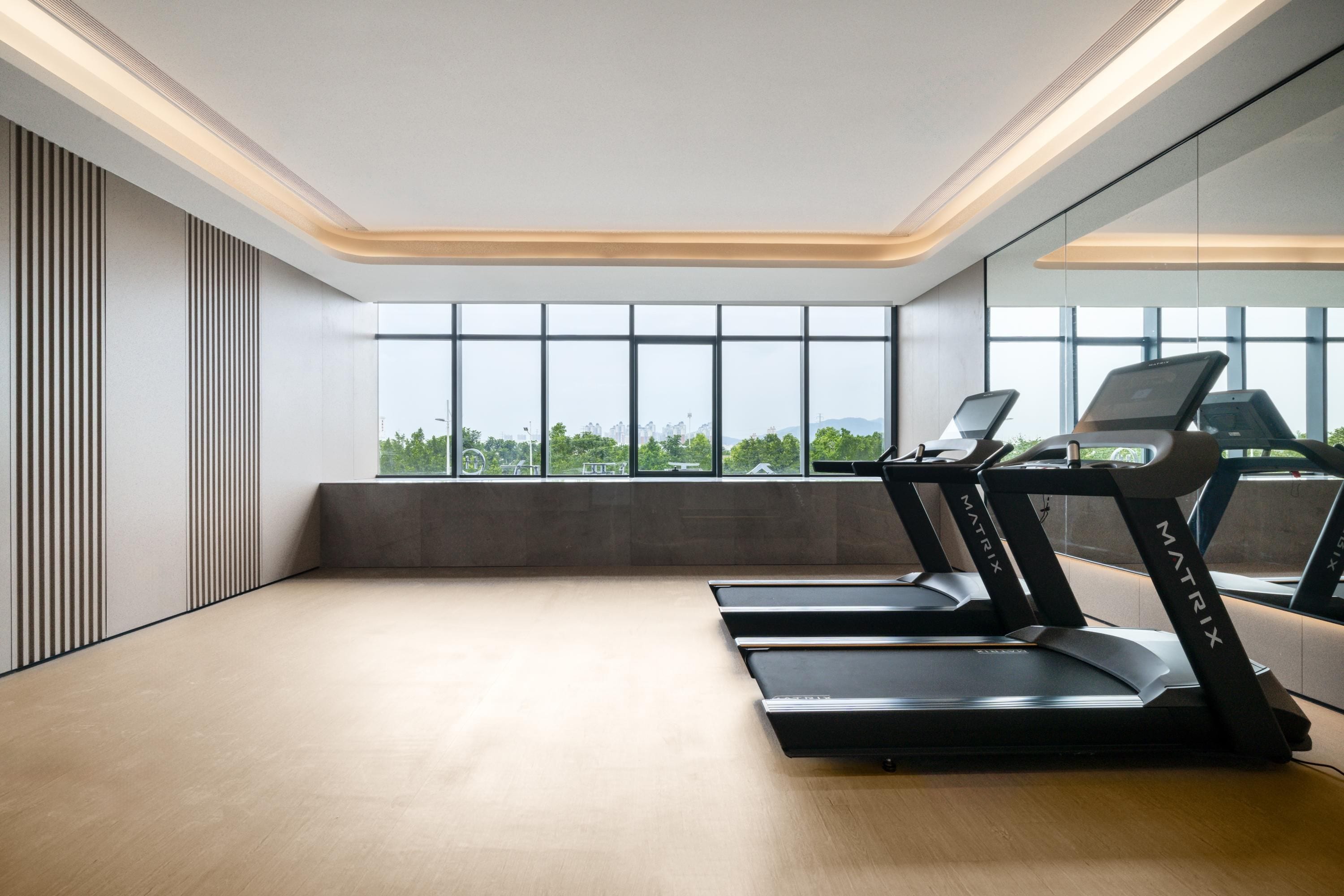 Un gimnasio moderno con cintas de correr, ventanas amplias y un diseño minimalista.
