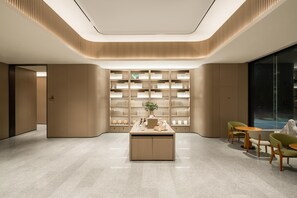 A modern interior with a central island, seating area, and a wall of shelves. - Ji Hotel Guangzhou North Railway Station (Guangzhou)