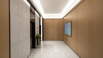 A modern hallway with a marble floor, a potted plant, and a framed picture on the wall.