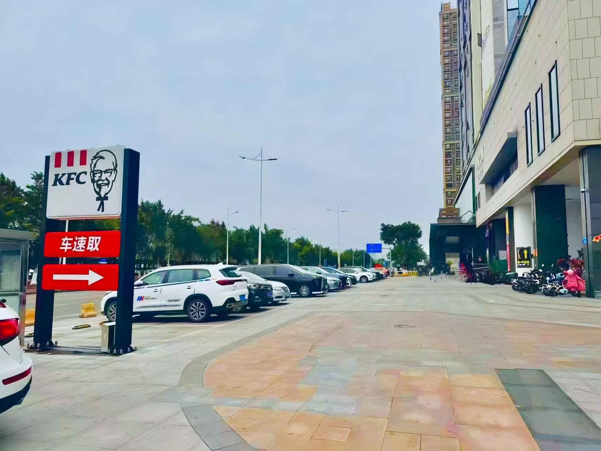 Un estacionamiento con autos y el letrero de KFC.
