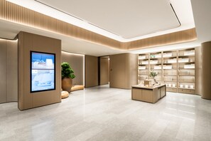 En modern hotellobby med en digital skärm, en receptionsdisk och en stor bokhylla.
