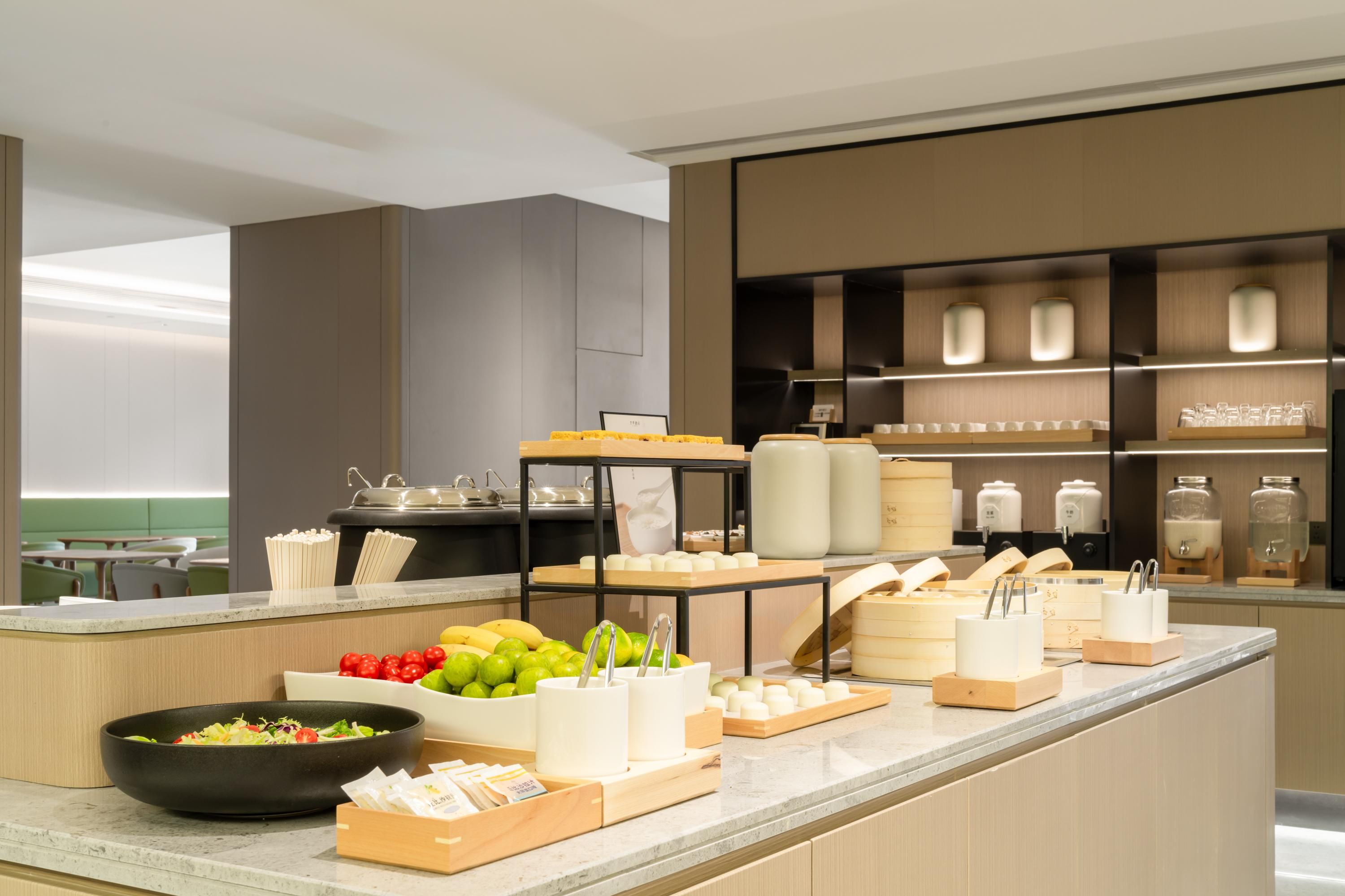 A modern kitchen with a marble countertop, various food items, and storage shelves.