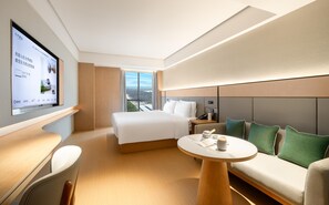 A modern hotel room with a large bed, a sofa, a small table, and a TV mounted on the wall. - Ji Hotel Guangzhou North Railway Station (Guangzhou)