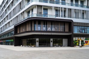 Un hotel moderno con una entrada curva, grandes ventanales y un cartel que indica que se trata de un hotel.