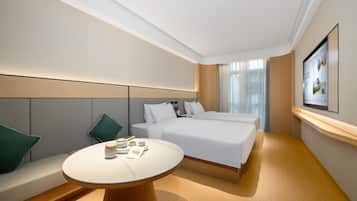 Quarto de hotel moderno com uma cama grande, uma mesa redonda com abajur e uma TV na parede.