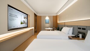 A hotel room with two beds, a TV mounted on the wall, a small table with a lamp, and a bedside table with a phone and a cup. - Ji Hotel Guangzhou Tianhe Smart City Wetland Park (Guangzhou)