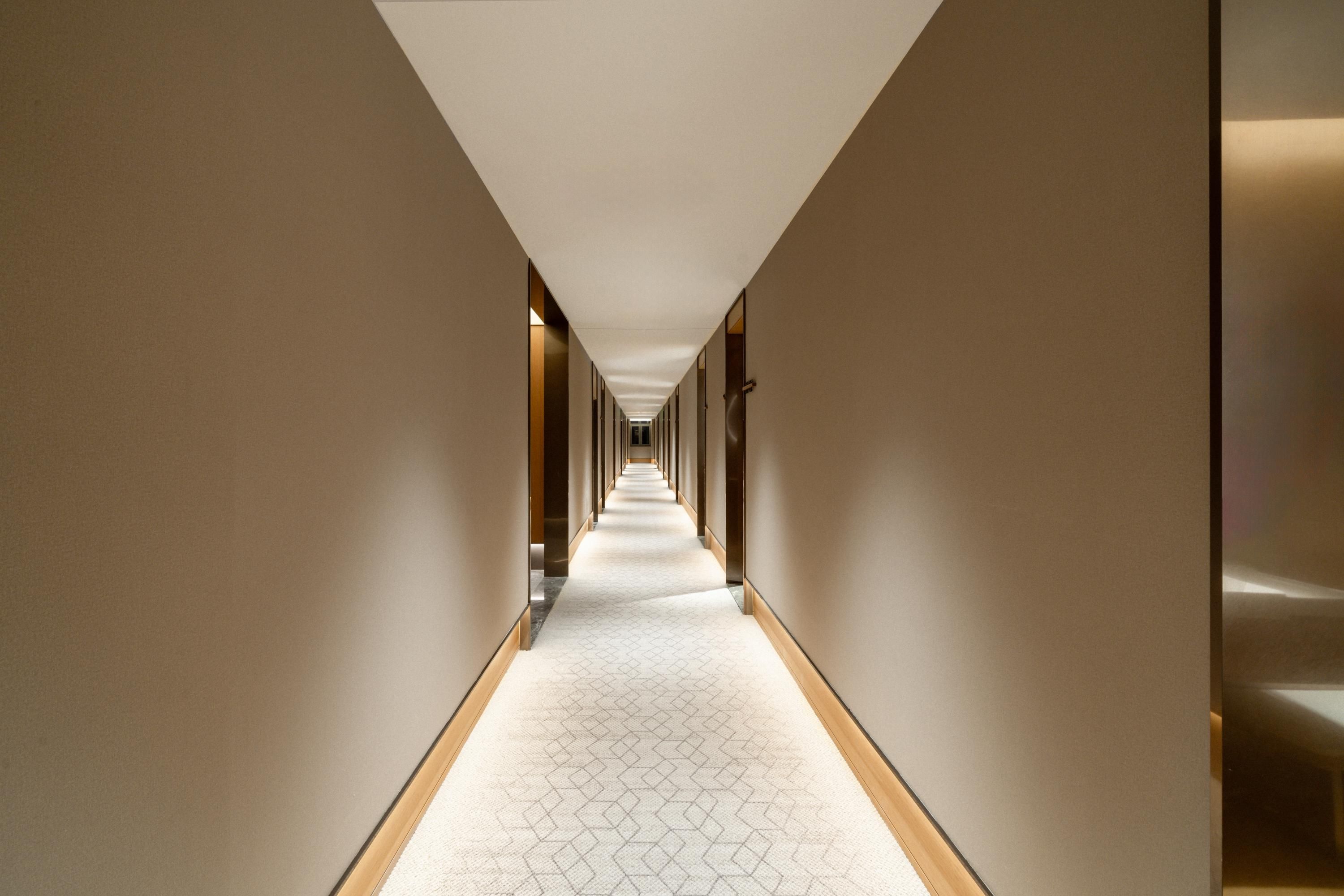 A long, narrow hallway with a patterned carpet and beige walls.