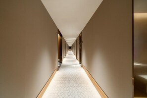 Un pasillo largo y estrecho con alfombra estampada y paredes color beige.