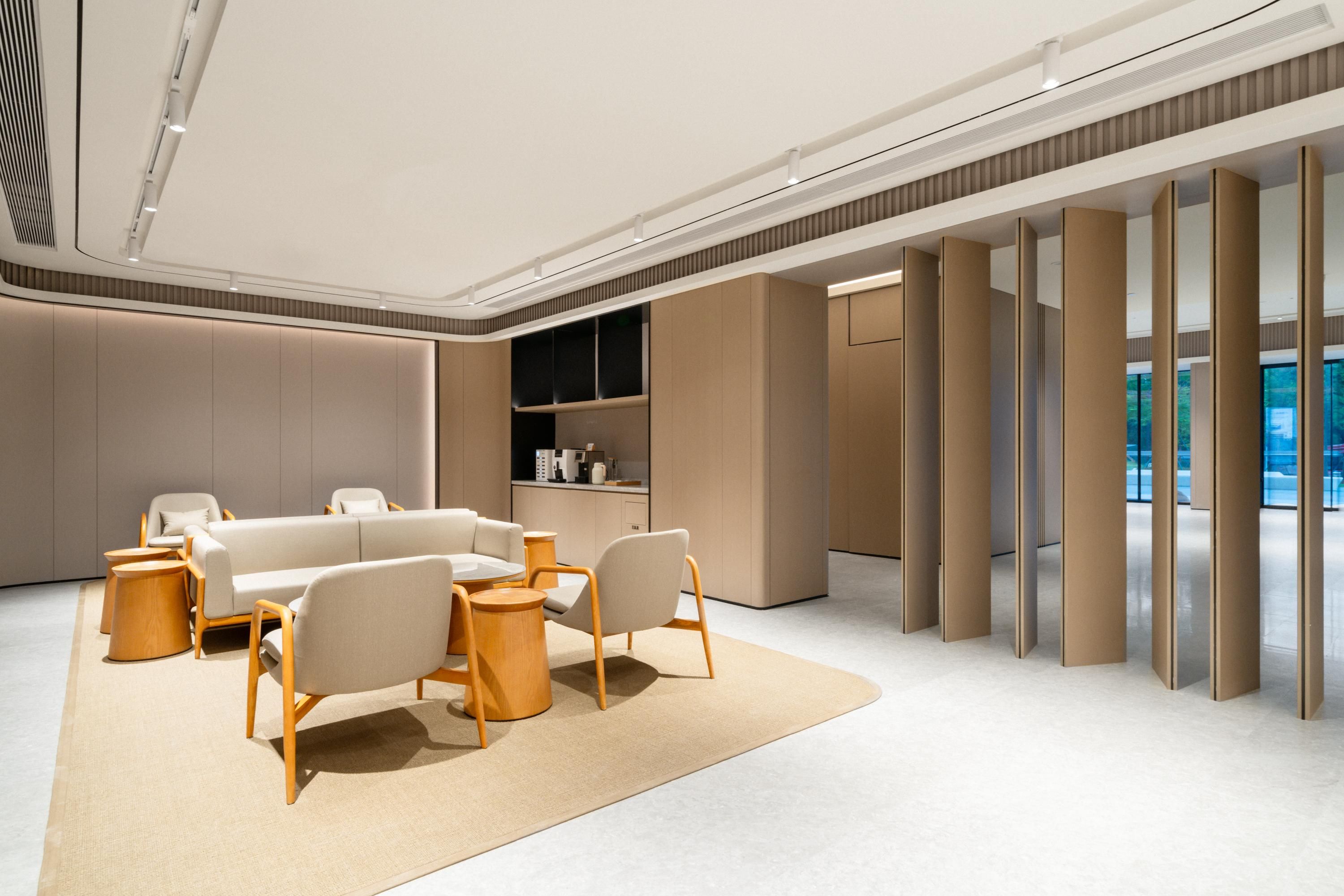A modern, well-lit lounge area with a sofa set, wooden side tables, and a large window offering a view.