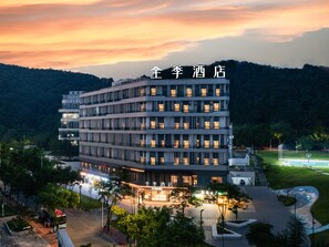 A multi-story hotel with a modern design, featuring a central courtyard and a view of the surrounding landscape.