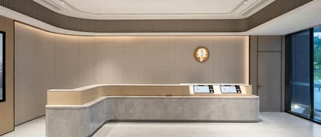 A modern reception area with a curved reception desk, a digital display, and a wall-mounted sign.