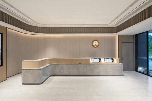 A modern reception area with a curved reception desk, a digital display, and a wall-mounted sign.