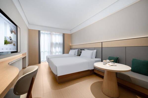 Una habitación de hotel moderna con una cama grande, un escritorio, una mesa redonda y un televisor en la pared.