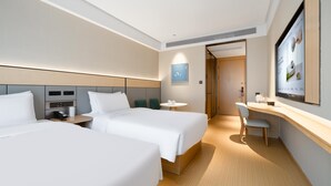 A hotel room with two beds, a desk, a chair, a small table, and a television. - Ji Hotel Guangzhou Tianhe Smart City Wetland Park (Guangzhou)