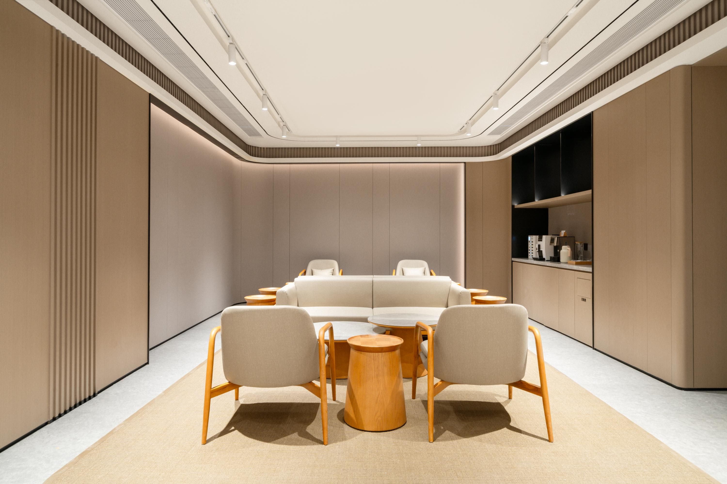 A modern interior with a sofa, two chairs, a round table, and built-in shelving.