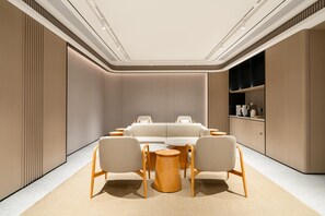 A modern interior with a sofa, two chairs, a round table, and built-in shelving.