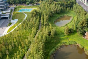 Eine Vogelperspektive eines Parks mit Basketballplatz, Spazierwegen und einem Teich.