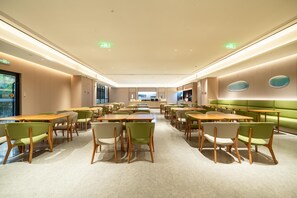 A spacious dining area with multiple tables and chairs, a green cushioned bench, and a modern ceiling design. - Ji Hotel Guangzhou Sun Yat-sen University Metro (Guangzhou)