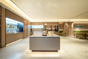 A modern, well-lit hotel lobby with a central reception desk, seating area, and a kitchenette. - Ji Hotel Guangzhou Sun Yat-sen University Metro (Guangzhou)