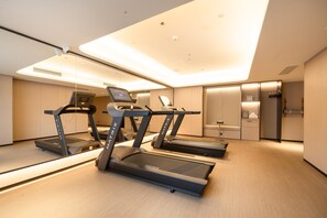 A modern fitness room with three treadmills, a digital screen, and a well-lit ceiling. - Ji Hotel Guangzhou Sun Yat-sen University Metro (Guangzhou)