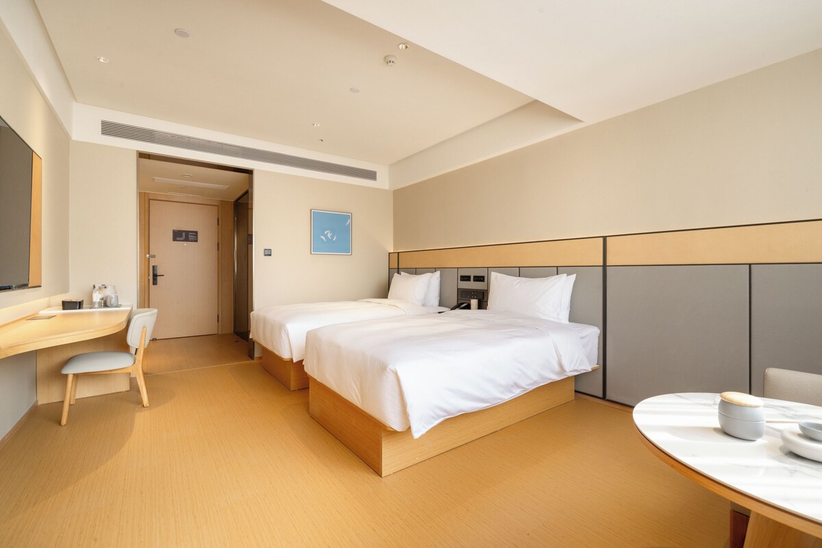 A modern hotel room with a large bed, a desk, and a small table.