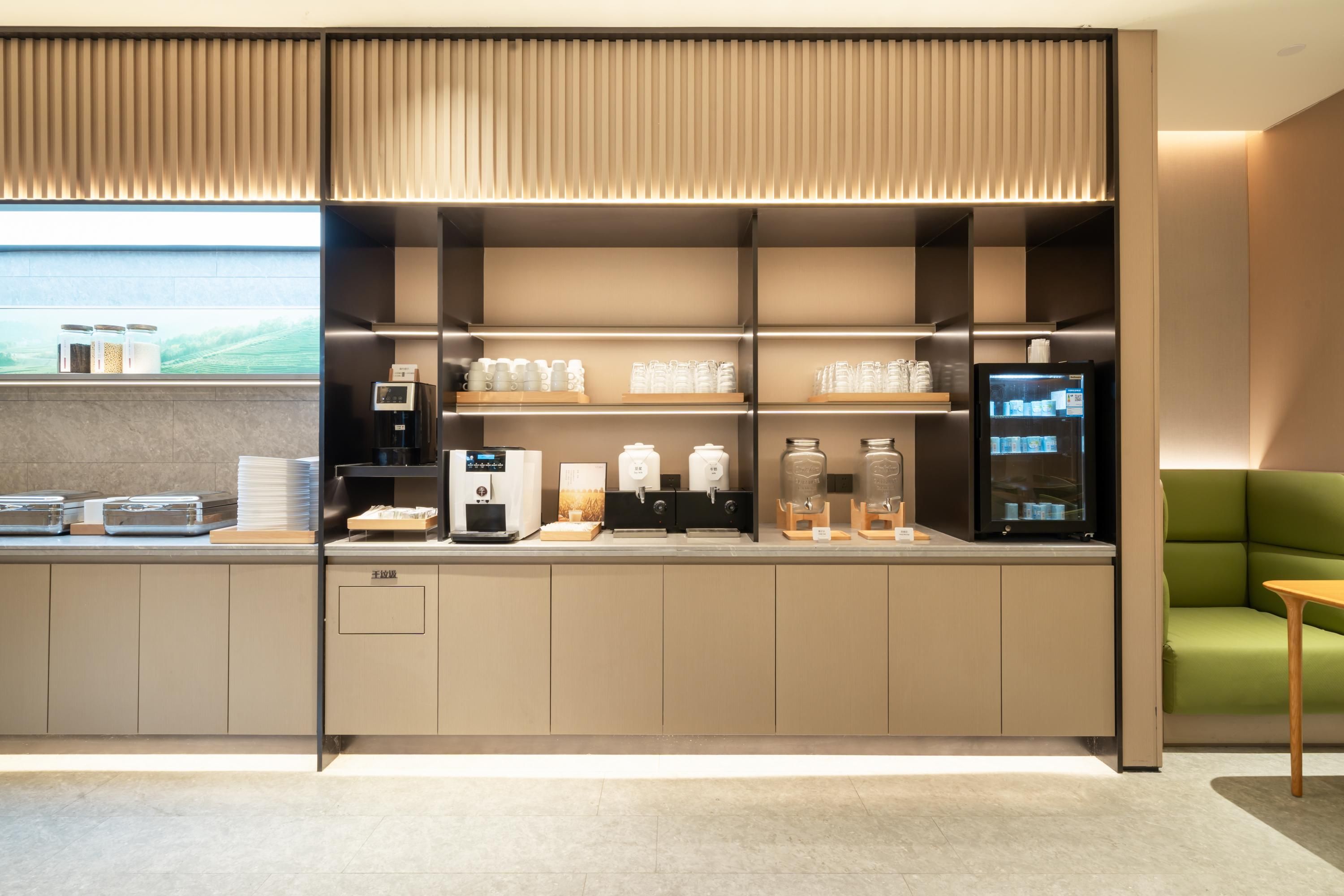 Una kitchenette moderna con electrodomésticos integrados, una cafetera y un refrigerador.