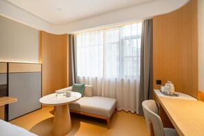 A modern hotel room with a sofa, a round table, a desk, and a large window with curtains. - Ji Hotel Guangzhou Sun Yat-sen University Metro (Guangzhou)