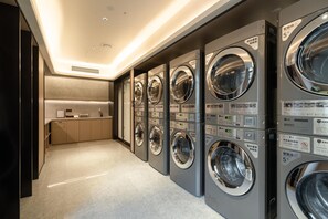 A row of modern, stainless steel front-loading washers in a commercial setting. - Ji Hotel Guangzhou Sun Yat-sen University Metro (Guangzhou)
