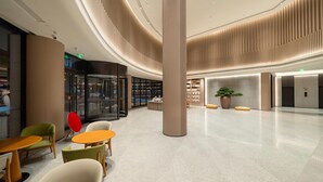 A spacious lobby with a modern design, featuring a central column, seating area with tables and chairs, and a large potted plant. - Ji Hotel Guangzhou Sun Yat-sen University Metro (Guangzhou)