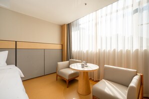 A hotel room with a bed, two armchairs, a small round table, and a large window with sheer curtains. - Ji Hotel Guangzhou Sun Yat-sen University Metro (Guangzhou)