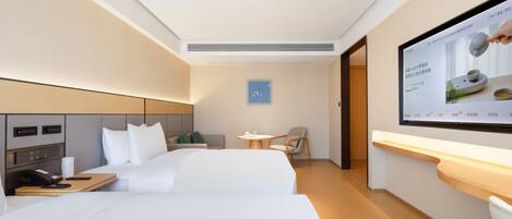 A hotel room with a bed, bedside table, chair, and a television screen displaying an advertisement.