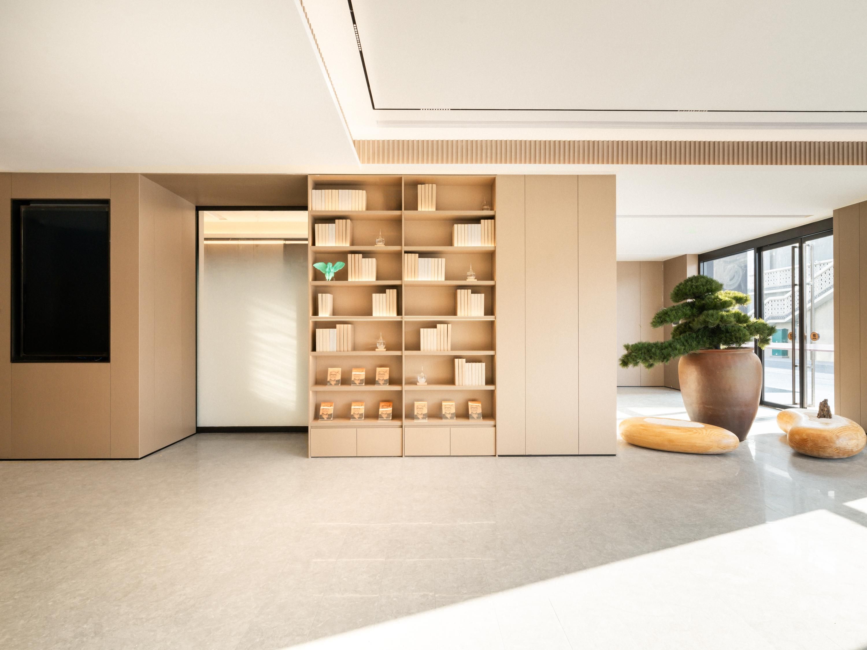 Ein modernes Interieur mit einer großen Bücherwand, einer Topfpflanze und einem minimalistischen Design.