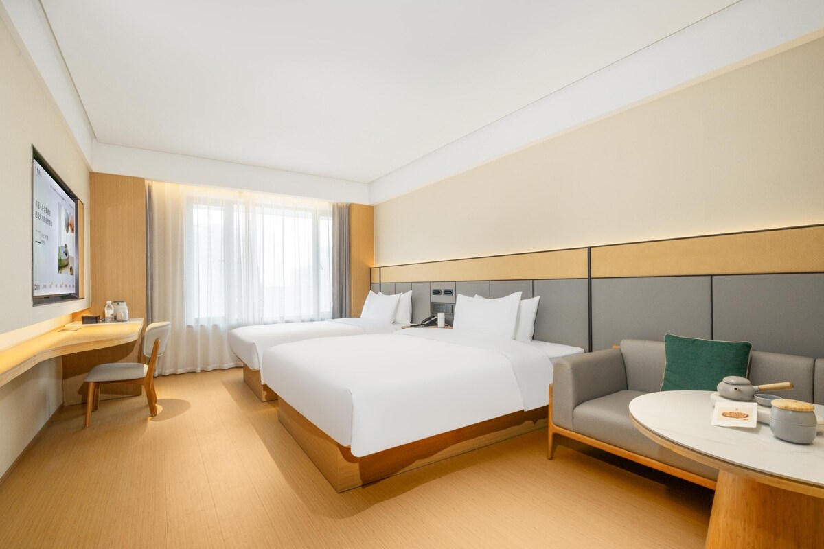 A hotel room with a large bed, a sofa, a desk, and a small table.