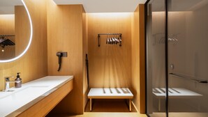A modern bathroom with a wooden vanity, a large mirror, a towel rack, and a glass shower enclosure. - Ji Hotel Guangzhou Baiyun Tinggang Metro Station (Guangzhou)