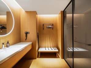 Une salle de bain moderne avec un meuble-lavabo en bois, un grand miroir, un porte-serviettes et une cabine de douche en verre.