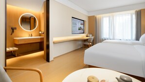 A hotel room with a bed, a desk, a chair, a round mirror, a TV, and a window with curtains. - Ji Hotel Guangzhou Baiyun Tinggang Metro Station (Guangzhou)