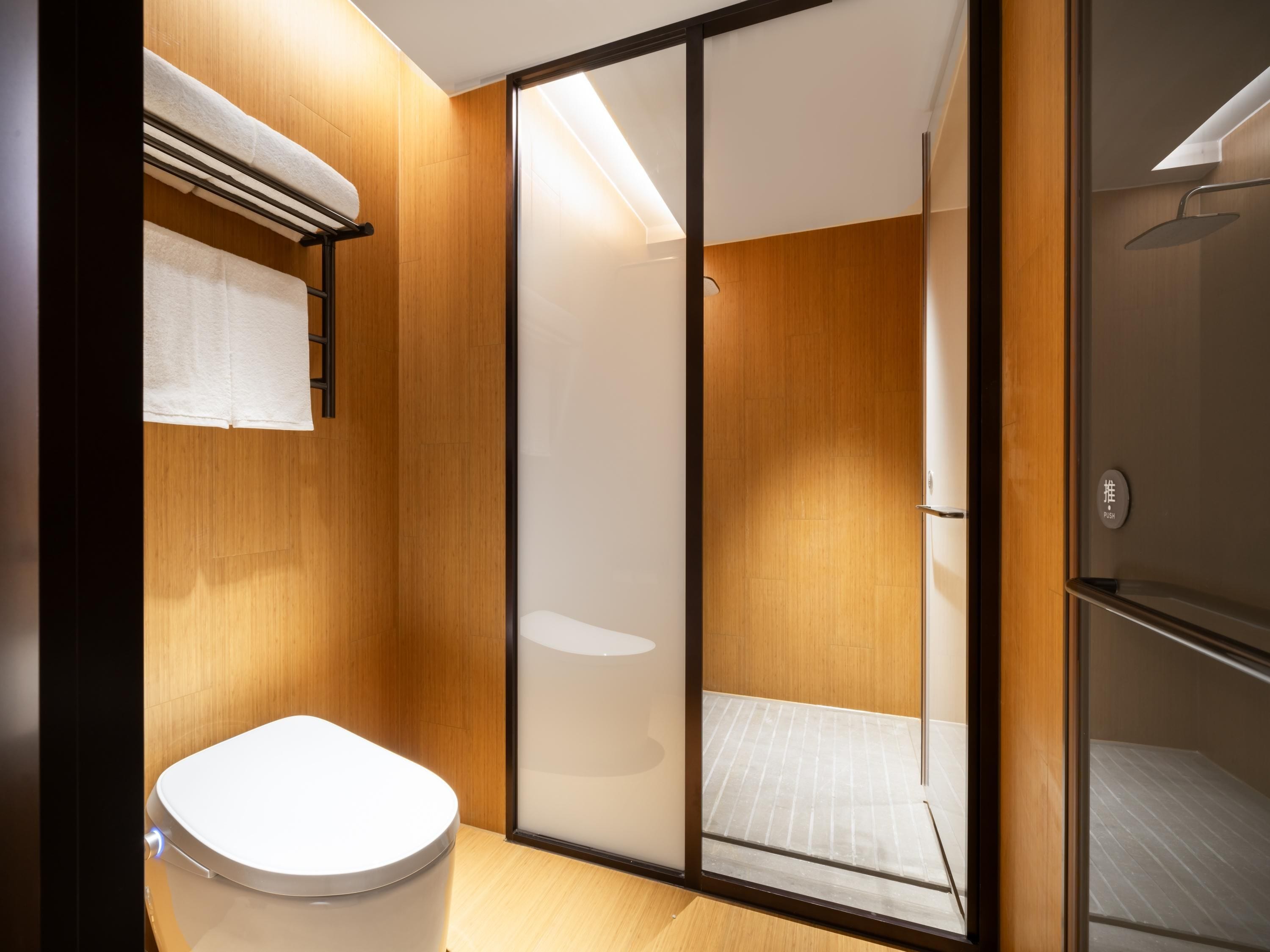 A modern bathroom with a toilet, a towel rack, and a shower area.