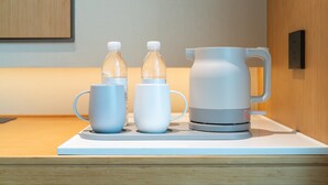 A kitchen counter with a coffee maker, two bottles, and a mug. - Ji Hotel Guangzhou Baiyun Tinggang Metro Station (Guangzhou)