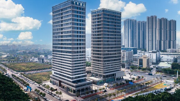 Two high-rise buildings with a modern architectural design, surrounded by a cityscape with other high-rise buildings in the background. - Ji Hotel Guangzhou Baiyun Tinggang Metro Station (Guangzhou)
