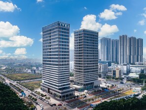 Dos edificios de gran altura con un diseño arquitectónico moderno, rodeados por un paisaje urbano con otros edificios altos al fondo.