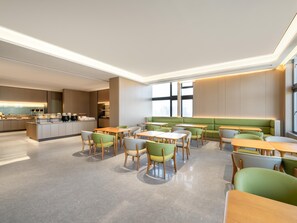 Un comedor moderno con una isla central, asientos acolchados verdes y una cocina al fondo.