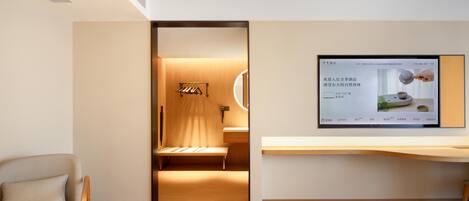 A modern hotel room with a bed, a desk, and a television mounted on the wall.