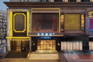 A hotel entrance with a modern design, featuring a prominent entrance with steps leading up to the door, a sign with the hotel name, and a traditional architectural element on the right. - Ji Hotel Guangzhou Modiesha Metro Station (Guangzhou)