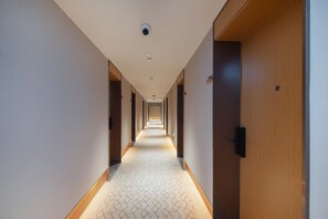 A hotel hallway with a patterned carpet, wooden doors, and recessed lighting. - Ji Hotel Guangzhou Modiesha Metro Station (Guangzhou)