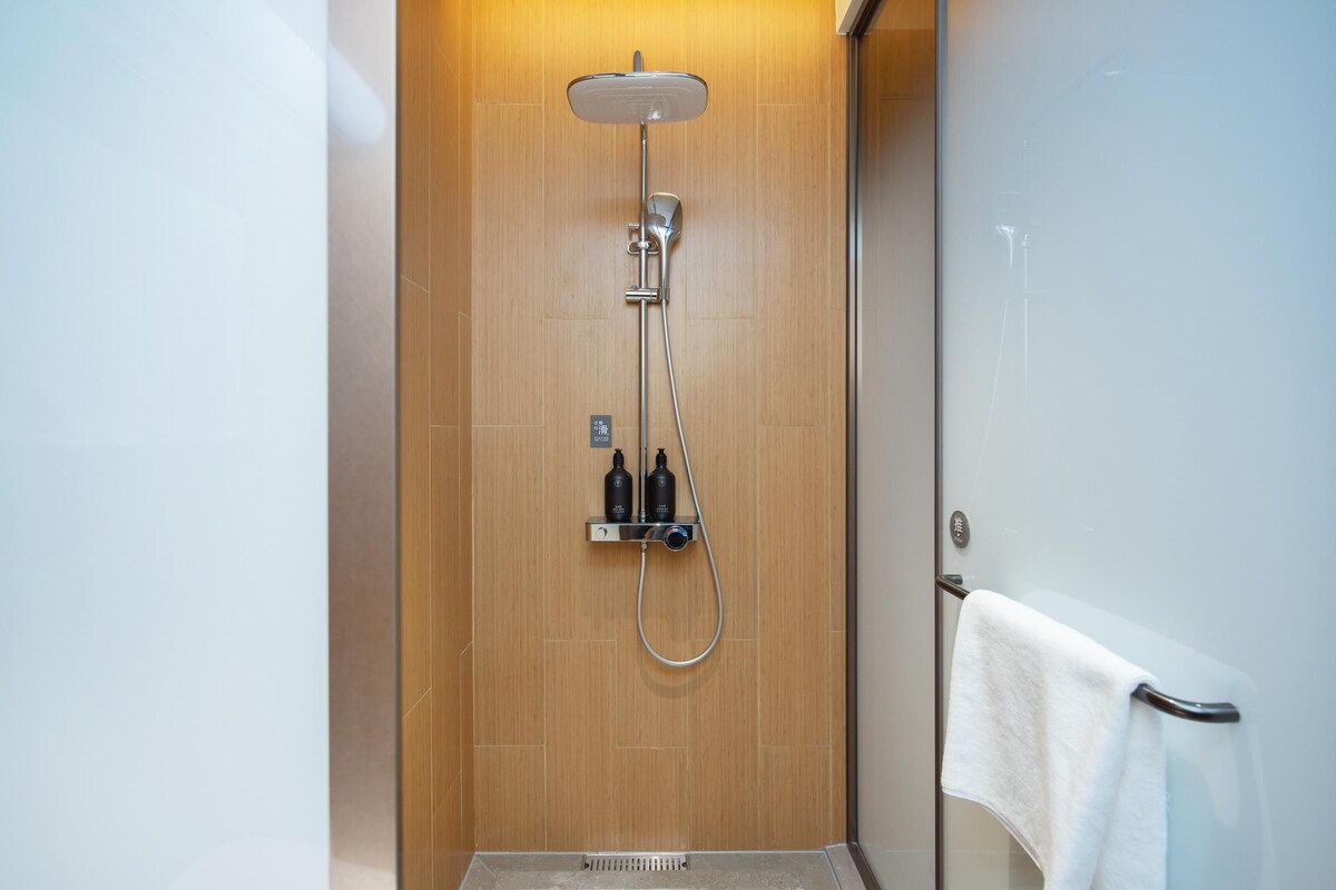 A modern shower with a handheld showerhead and a wall-mounted control panel.