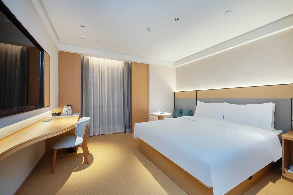 Une chambre d’hôtel moderne, dotée d’un grand lit, d’un bureau et d’une chaise.