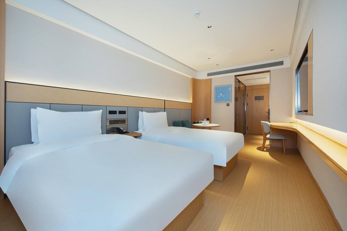 Une chambre d’hôtel avec deux lits, un bureau et une chaise.