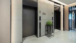 Um elevador moderno com acabamento metálico, uma pequena planta em vaso e um painel de controle digital.