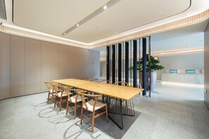 A modern conference room with a long table and chairs, a reception desk, and a large potted plant. - Ji Hotel Guangzhou Modiesha Metro Station (Guangzhou)