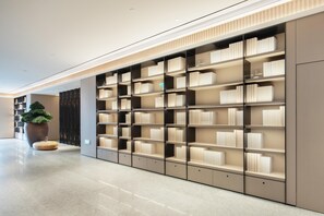 A modern library with multiple bookshelves, a large potted plant, and a polished floor. - Ji Hotel Guangzhou Modiesha Metro Station (Guangzhou)